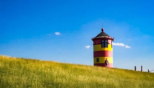 East Frisia - Krummhörn - the yellow-red striped Pilsum lighthouse on the dyke - angiestravelroutes.com