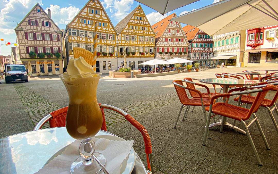 Herrenberg marketplace - iced coffee on the table - in the background a row of half-timbered houses and the market fountain - angiestravelroutes.com