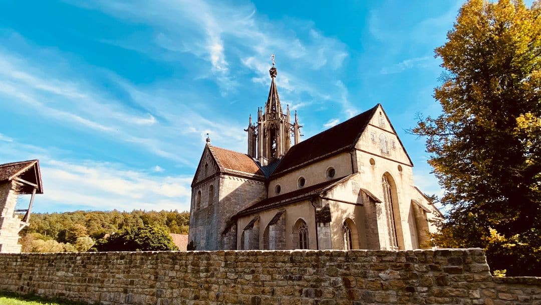 Kloster und Schloss Bebenhausen bei Tübingen, Baden-Württemberg - die hochgotische Klosterkirche hinter einem Teil der Klostermauer - angiestravelroutes.com