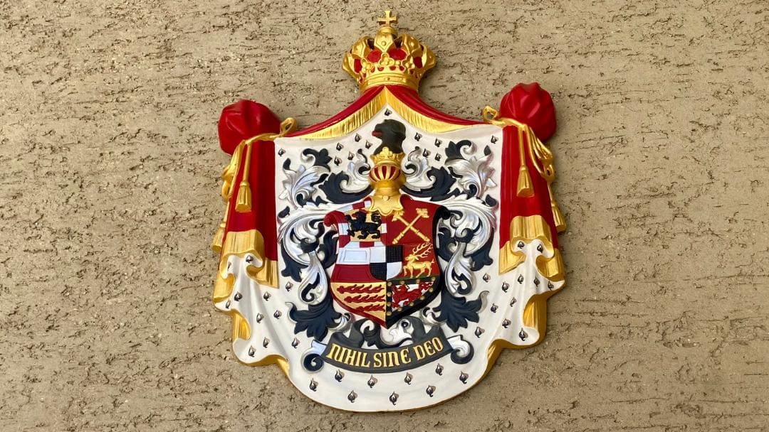 Hohenzollernschloss Sigmaringen, Wappen der Hohenzollern neben der Eingangstür zum Schloss, Farben: rot, weiß, schwarz, silber und gold, in der Mitte die "Zollernvierung" - ein gevierteilter Schild in Silber und Schwarz - unten Aufschrift "Nihil sine Deo".