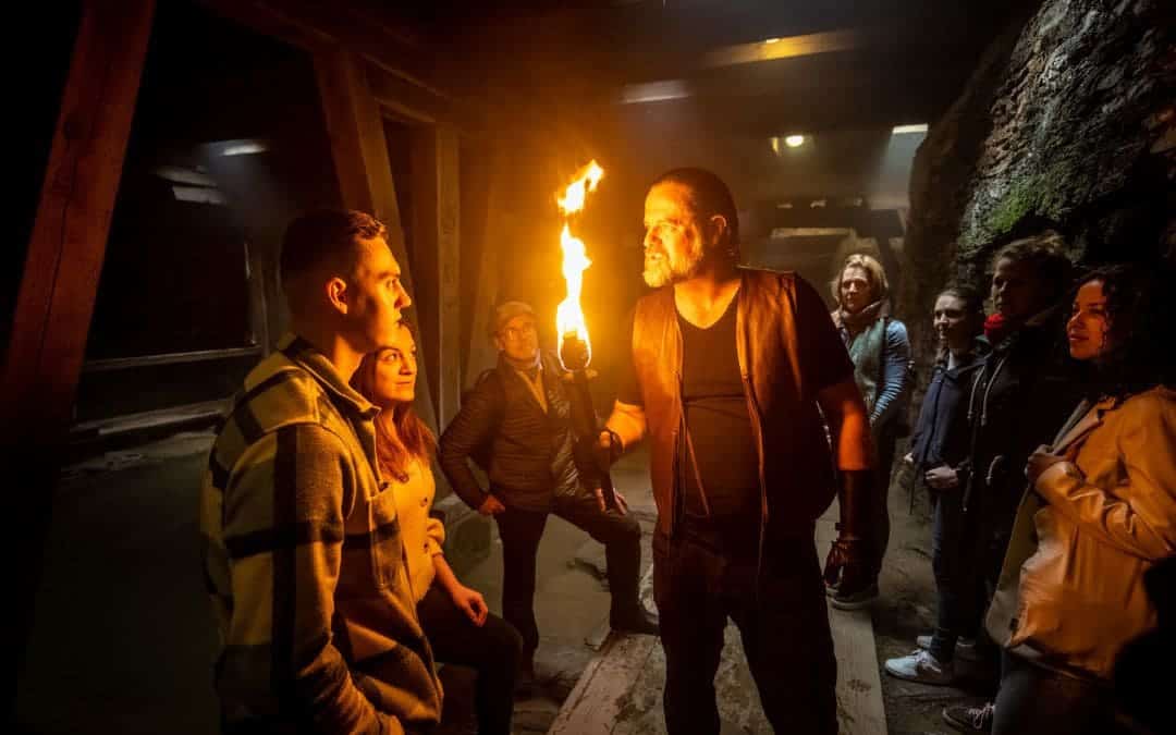 Valerius spricht mit einer Fackel in der Hand im Keller des Amphitheaters mit den Zuschauern.