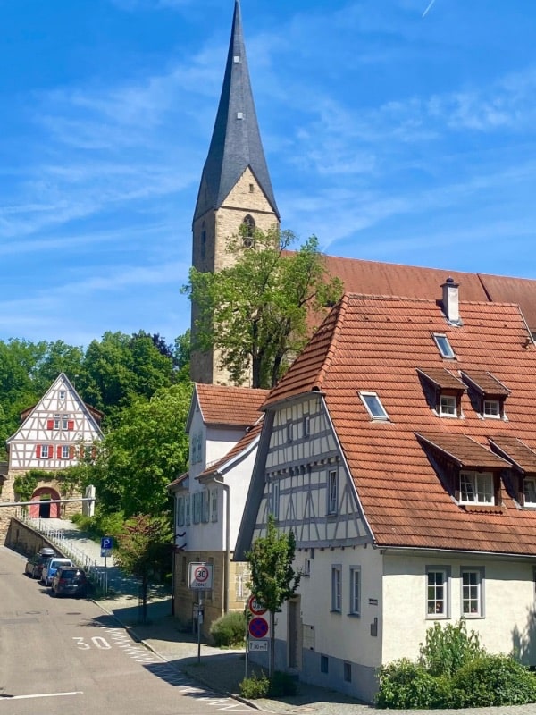 Marbach am Neckar - Church tower of the Alexanderkirche, in front of it a half-timbered house - angiestravelroutes.com