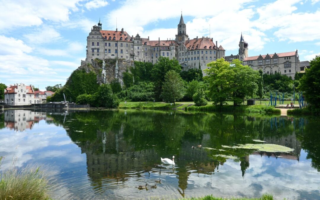 Hohenzollernschloss Sigmaringen - Blick von der Donaubühne aufs Schloss, im Vordergrund die Donau, ein Schwan und eine Entenmutter mit Jungen im Wasser - angiestravelroutes.com