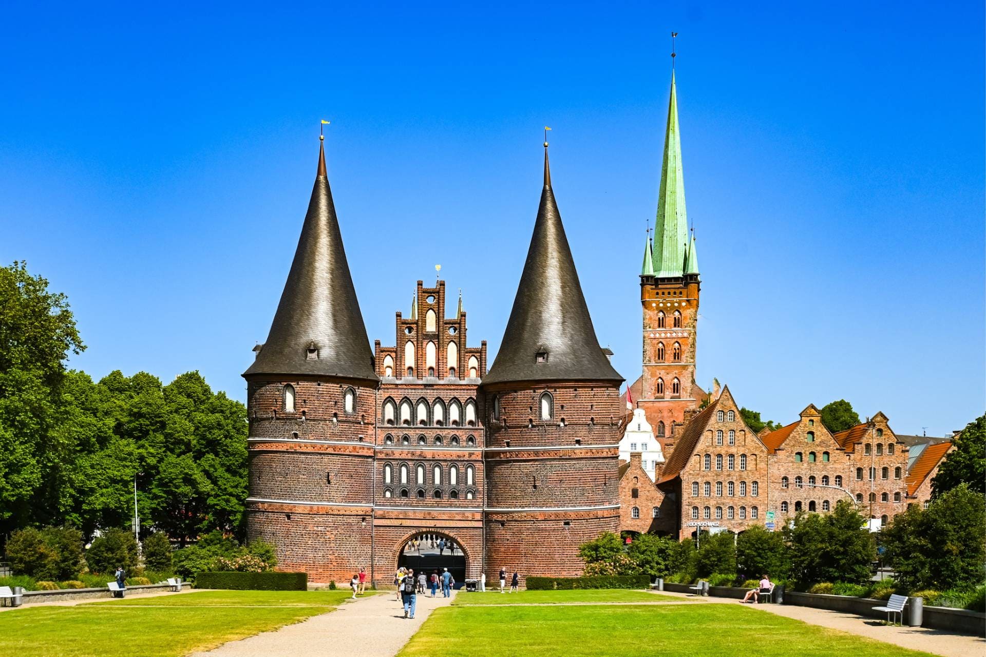 Beitragsbild Schönste Städte Deutschlands - Lübeck - Holstentor mit Salzspeicher und Petrikirche, alle aus rotem Backstein - fotografiert vom Holstentorplatz - angiestravelroutes.com