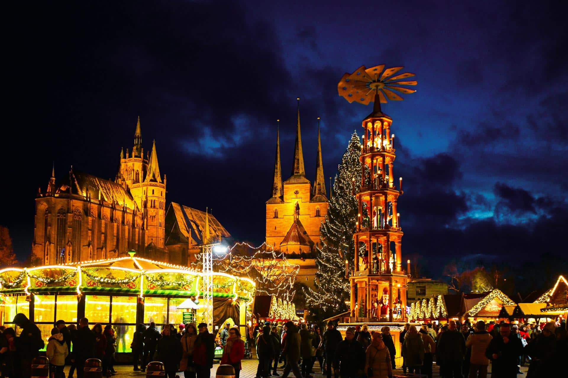 Weihnachtsmarkt Erfurt - beleuchteter Domplatz am Abend mit Weihnachtspyramide, Weihnachtsbaum und Weihnachtszelt im Vordergrund, der Dom und die St. Severi Kirche im Hintergrund - angiestravelroutes.com