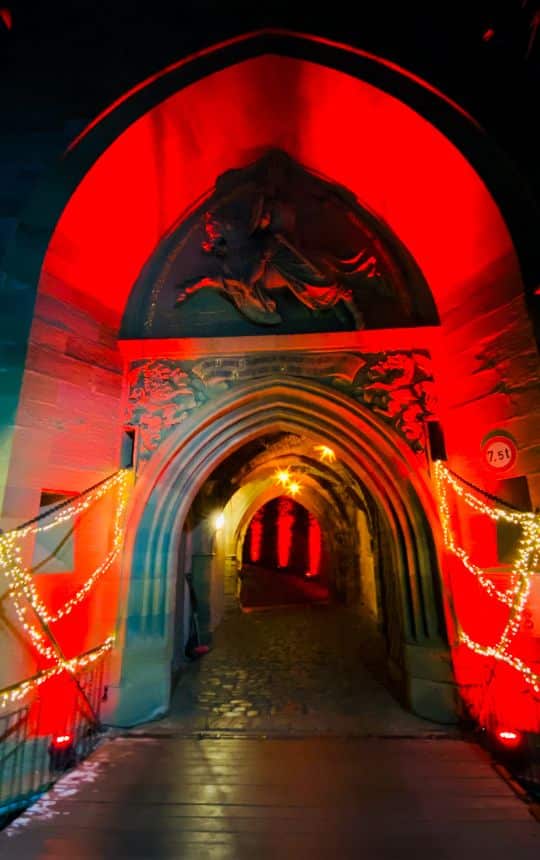 Hohenzollern Castle, Eagle Gate - glowing poinsettias hang in the red illuminated gate - angiestravelroutes.com