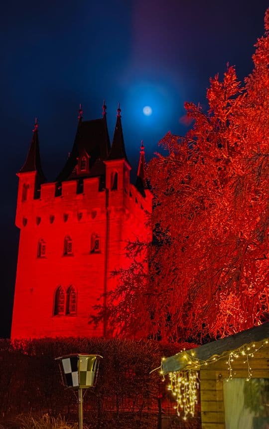 Hohenzollern Castle, Schnarrwacht bastion. The full moon shines above the red illuminated tower - angiestravelroutes.com