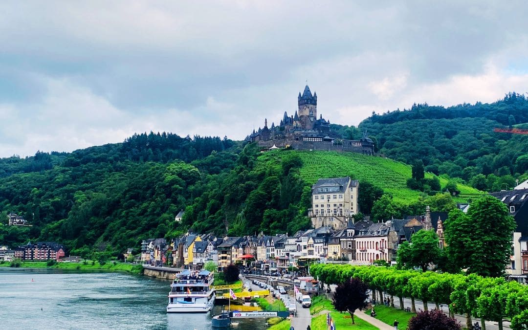 Cochem, view of the Moselle with boats moored along its banks and Reichsburg Castle towering over the town
