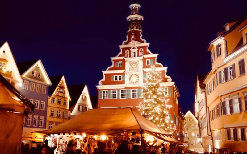 Esslingen Medieval Market and Christmas Market in the evening - Town Hall Square with Old Town Hall, in front of it the illuminated Christmas tree and market stalls - angiestravelroutes.com