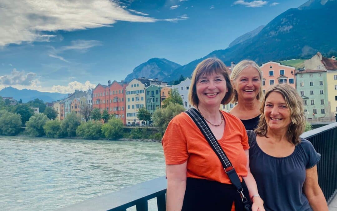 Innsbruck Innbrücke: Drei lachende Frauen vor dem Hintergrund der bunten Häuserzeile in der Mariahilfstraße - angiestravelroutes.com