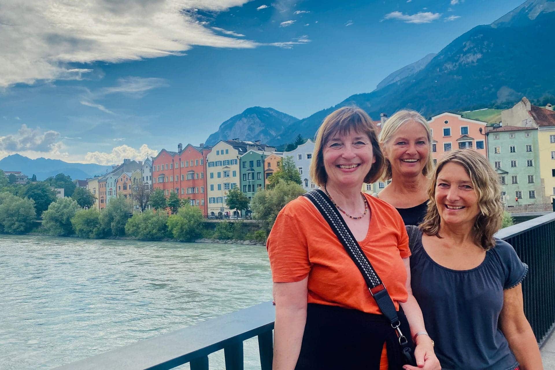 Innsbruck Innbrücke: Drei lachende Frauen vor dem Hintergrund der bunten Häuserzeile in der Mariahilfstraße - angiestravelroutes.com