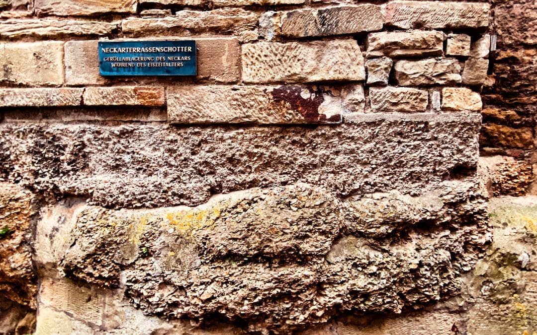 Below a residential building in the old town of Marbach are shell limestone deposits from the Ice Age. The sign above it reads "Neckar terrace gravel - debris deposits of the Neckar during the Ice Age"