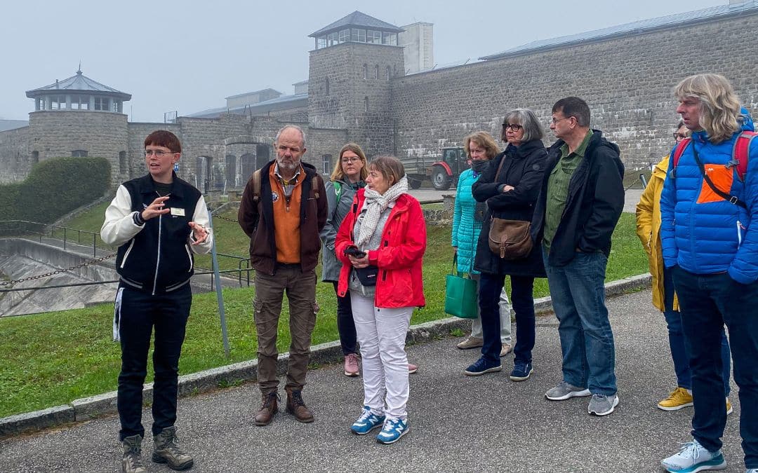 KZ-Gedenkstätte Mauthausen bei Linz, Österreich - diskutierende Gruppe, im Hintergrund die Mauern und Türme des ehemaligen Konzentrationslagers - angiestravelroutes.com