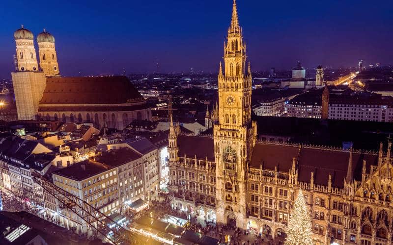 Munich Christmas market in the evening: aerial view of Marienplatz, city hall and Frauenkirche, in front of the city hall the illuminated Christmas tree - angiestravelroutes.com