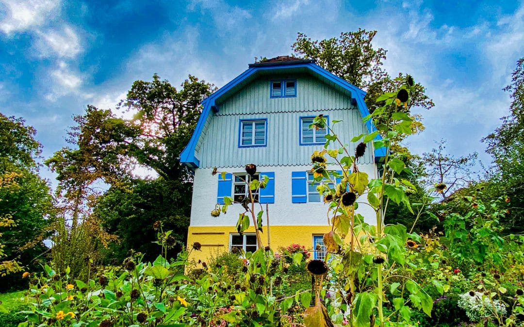 murnau-muenter-haus Münter-Haus in Murnau am Staffelsee mit blau-weißer Holzfassade und blühendem Garten.