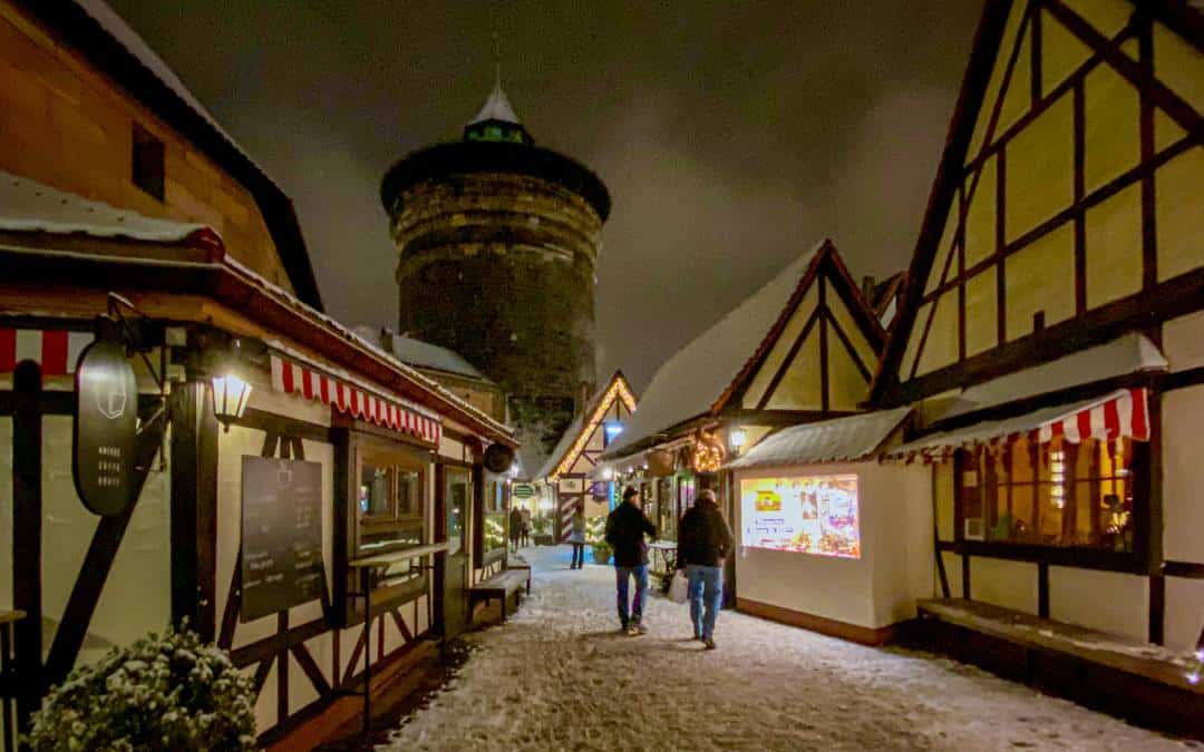 Handwerkerhof Nuremberg - taken during an evening walk in the Advent season - snow-covered alley and houses, in the background the Frauentorturm - angiestravelroutes.com