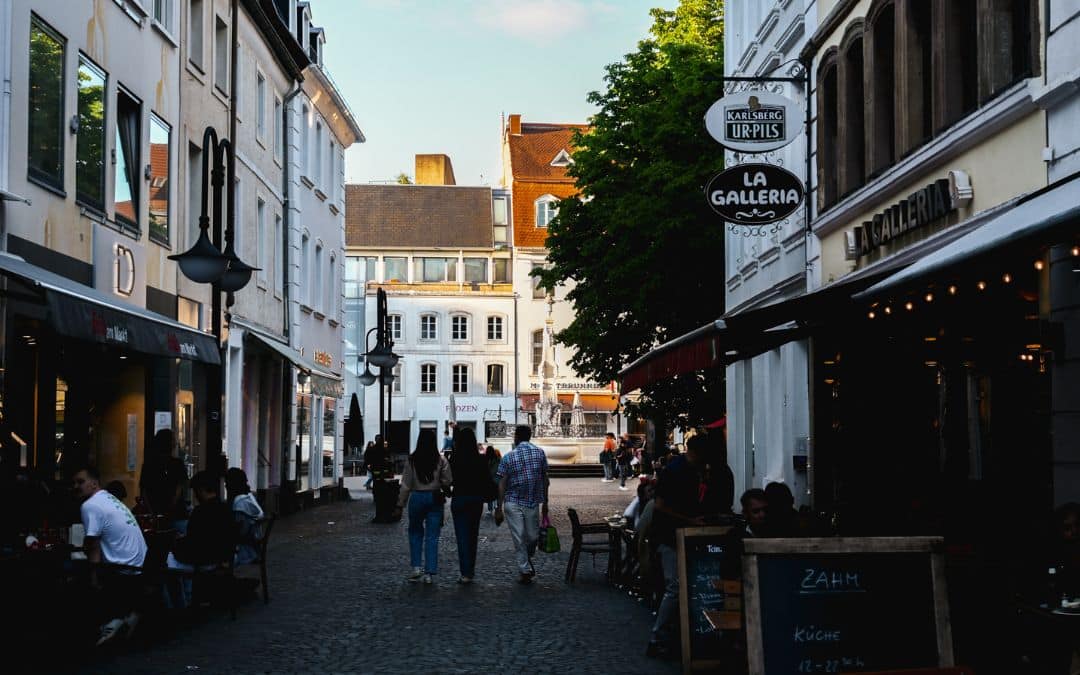 A bustling alley in Saarbrücken's Old Town with outdoor dining and a view of the Marktbrunnen