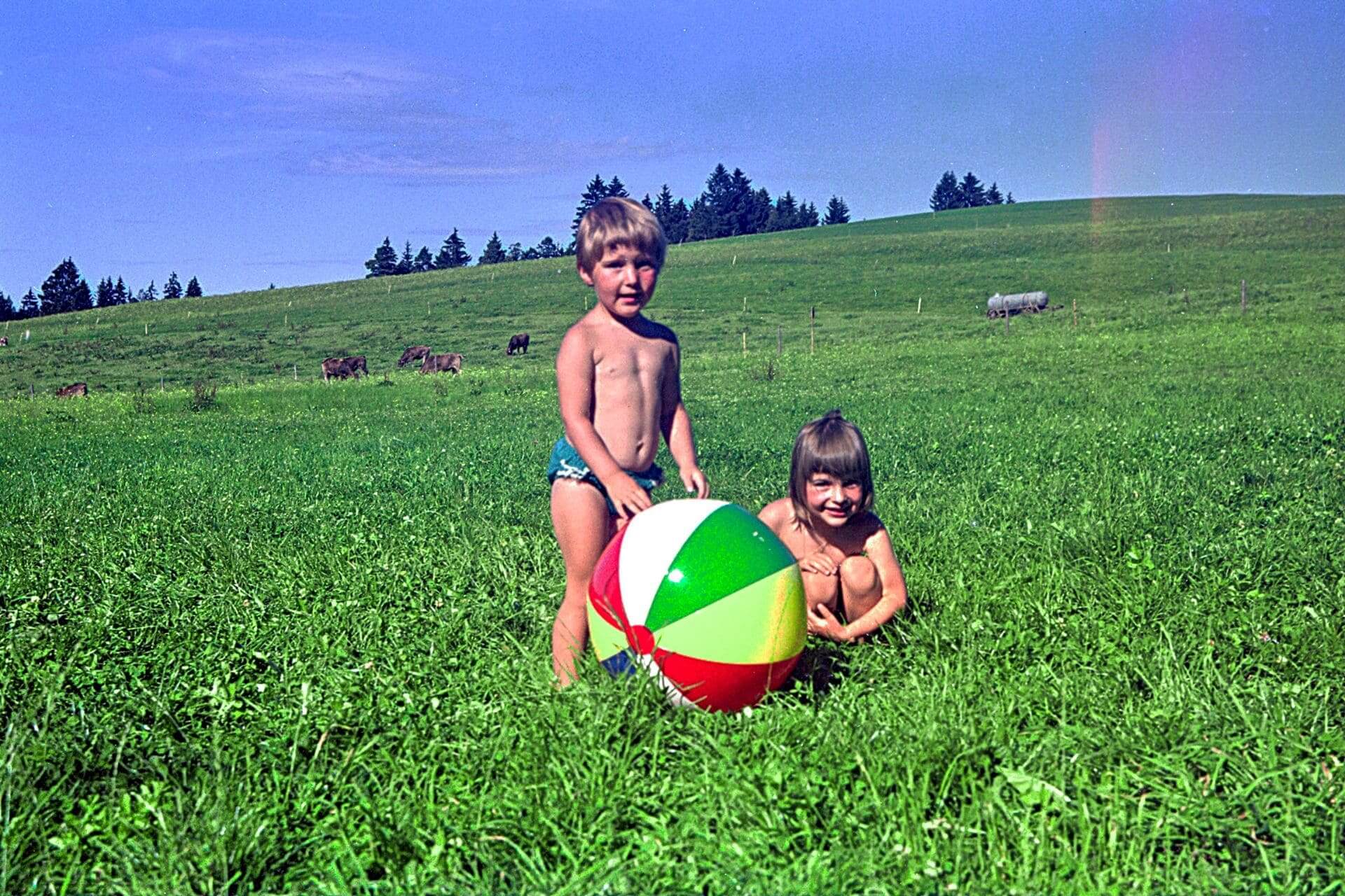 Schmutterweiher near Lechbruck, Bavaria, 1967 - my little sister (4, standing and me (5 years, squatting) with a colorful beach ball on a green alpine meadow - angiestravelroutes.com