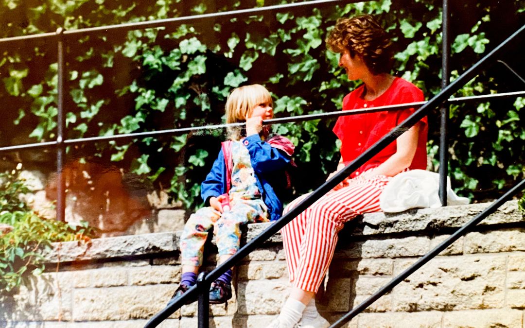 Sindelfingen, Old Town, 1992 - my daughter (5 years old) and I (wearing a red blouse and red and white striped trousers) sit on a wall in Sindelfingen behind a railing and look at each other - angiestravelroutes.com