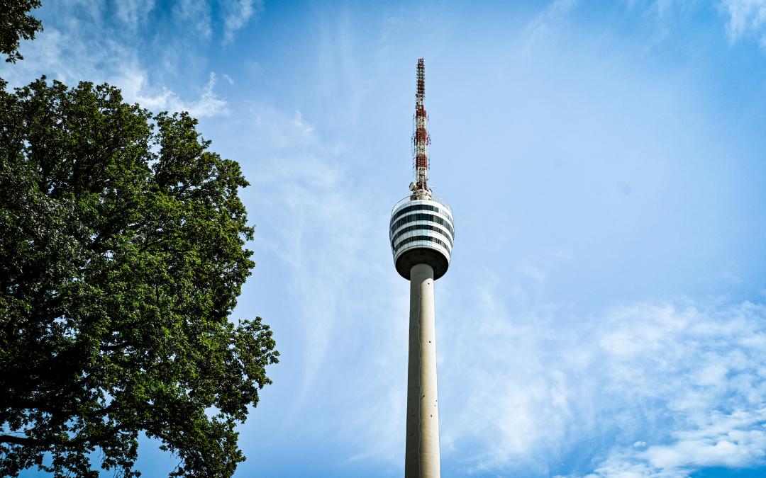 Fernsehturm Stuttgart - oberer Teil des Turmschafts, Turmkorb und Antenne vor dem blauen Himmel - links im Bild ein Baum - angiestravelroutes.com