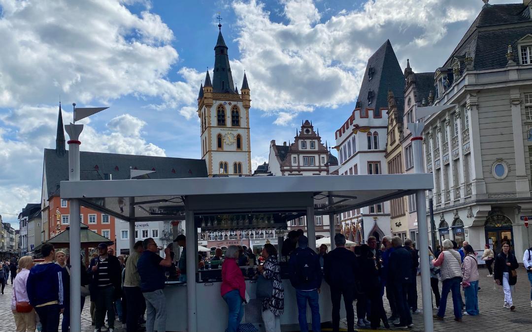 Gut besuchter Trierer Weinstand auf dem Hauptmarkt mit St. Gangolf im Hintergrund