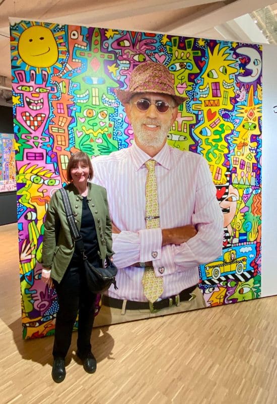 Neues Kunstmuseum Tübingen Angelika Klein in front of a large-format photo of James Rizzi standing in front of one of his works.