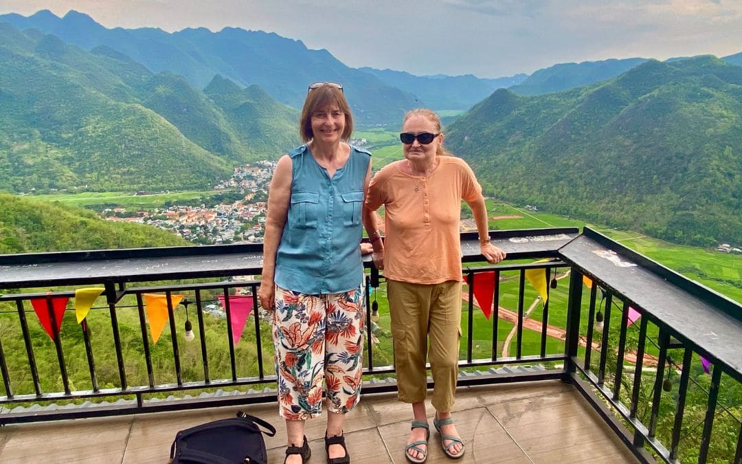 Mai Chau, Vietnam - zwei Frauen auf einer Aussichtsplattform, im Hintergrund die grüne Berglandschaft und das Dorf im Tal - angiestravelroutes.com