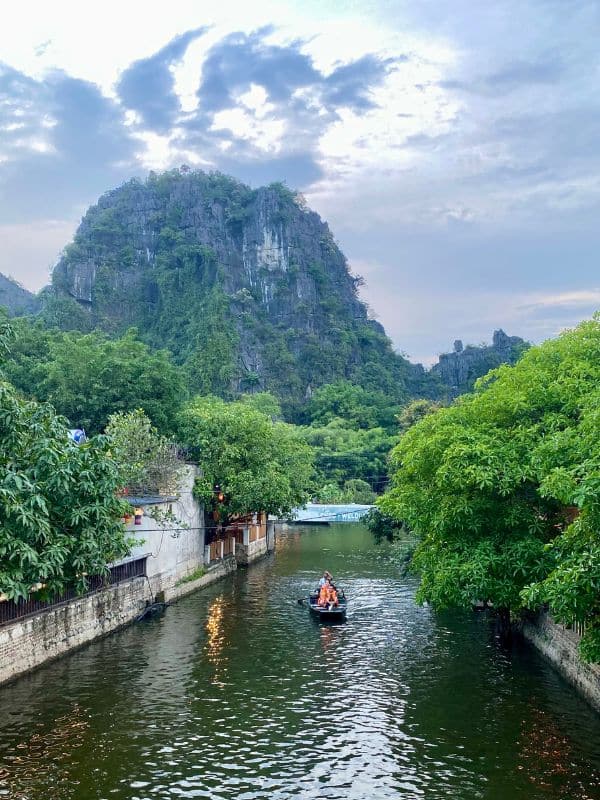 Ninh Binh, Tam Coc: Ruderboote auf den Ngô Đồng-Fluss, im Hintergrund ein gewaltiger, bewaldeter Karstkegel - angiestravelroutes.com