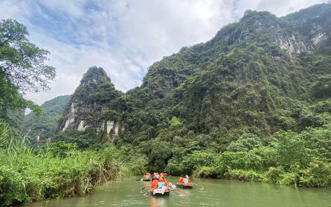 Vietnam, Ninh Binh, Trang An: Ruderboote mit Touristen auf dem Fluss Ngô Đồng zwischen den bewaldeten Karstfelsen - angiestravelroutes.com