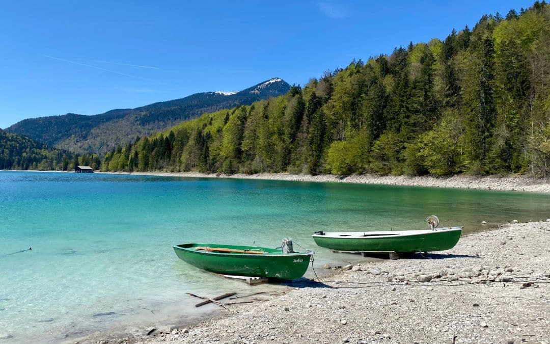 Zwergern peninsula - two turquoise rowing boats on the beach of the turquoise Walchensee, wooded mountains in the background