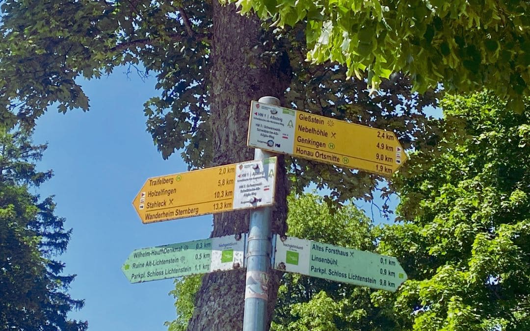 Wegweiser beim Schloss Lichtenstein, Schwäbische Alb: Grüne und gelbe Schilder, die Wanderwege in verschiedenen Richtungen anzeigen - angiestravelroutes.com
