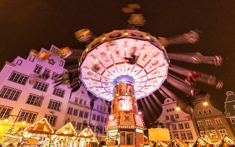 Christmas market Rostock: New market in the evening with chain carousel, Christmas market huts and gabled houses. - angiestravelroutes.com