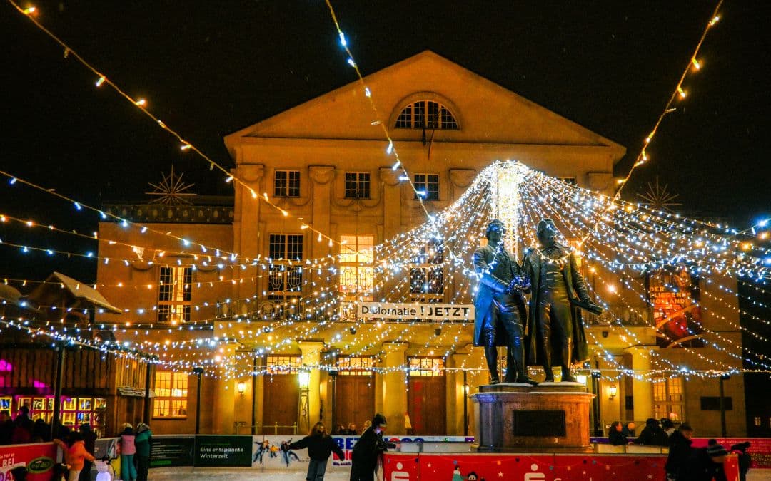 Weimar Christmas Thuringia - the Goethe-Schiller monument stands in the center of the ice rink in front of the German National Theater - a sky of fairy lights spans the ice rink - night shot - angiestravelroutes.com